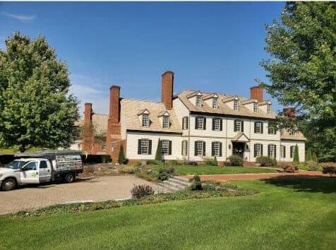 A large white house with a truck in front of it.