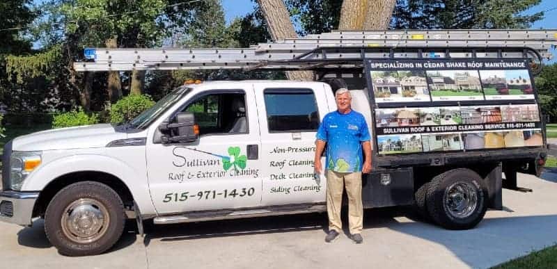 A man standing in front of a white truck with signs on it.